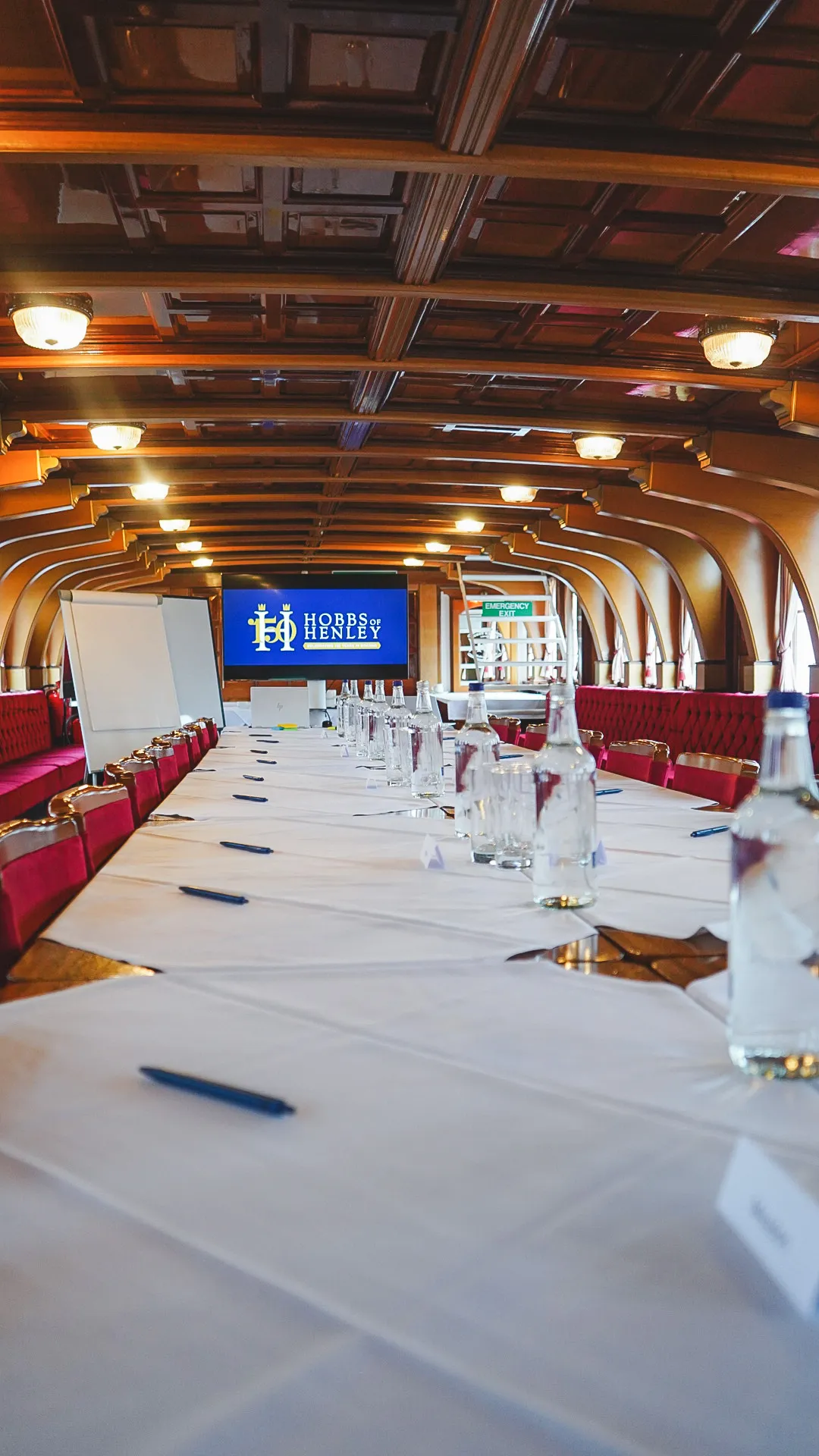 Inside a Hobbs of Henley boat, set up with tables for a corporate event.