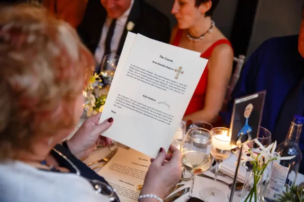Lady sat at a table reading a print out of the Henley-on-thames murder mystery cruise guests for the evening.